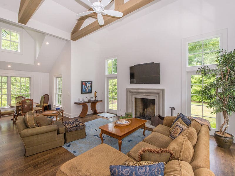 Family room remodel with TV over Old world cement mantel with 7” oak plank flooring and vaulted ceiling with ceiling fans and wood beams  in Boonton, New Jersey renovated by JMC Home Improvement Specialists