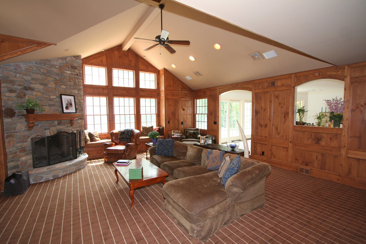 Authentic knotty pine paneling with ledge stone fireplace and vaulted ceiling with high hats and custom arches with panels in Morris County, NJ renovated by JMC Home Improvement Specialists