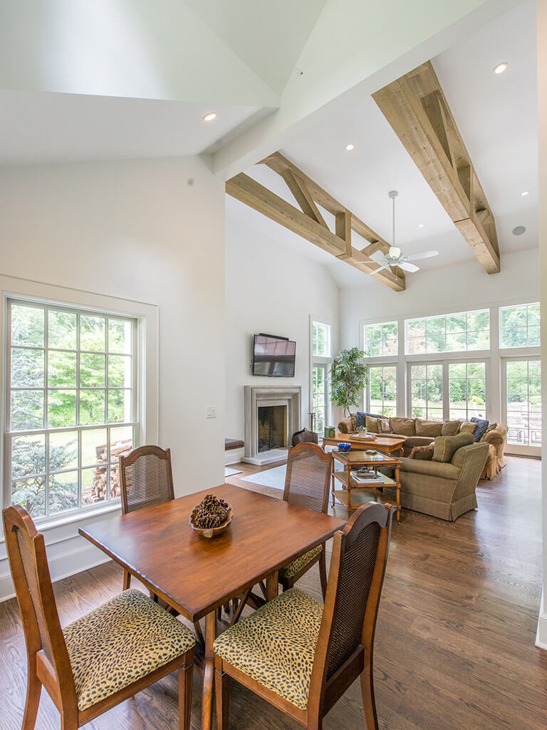 Corner view in rustic Family room remodel with 7” oak plank flooring, vaulted ceiling and reclaimed wood beams with ceiling fan and LED highhats with Andersen windows in Boonton, NJ renovated by JMC Home Improvement Specialists