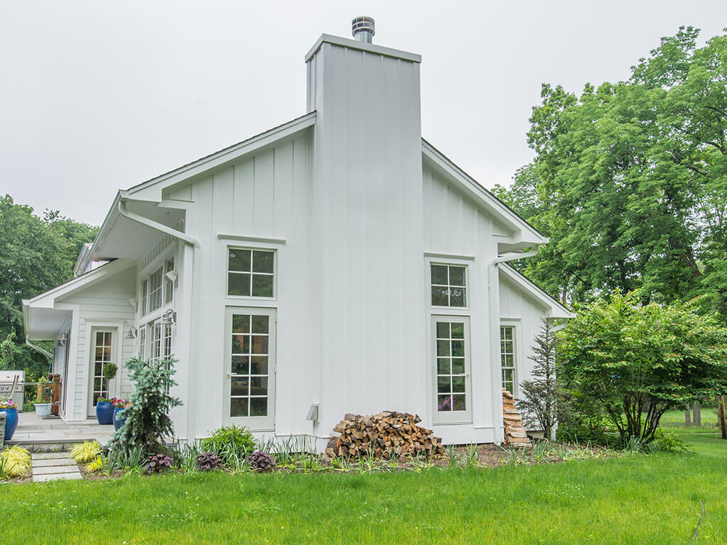 Exterior view of rustic Family room remodel board and batten siding and zero clearance fire place with Andersen windows in Boonton, NJ renovated by JMC Home Improvement Specialists
