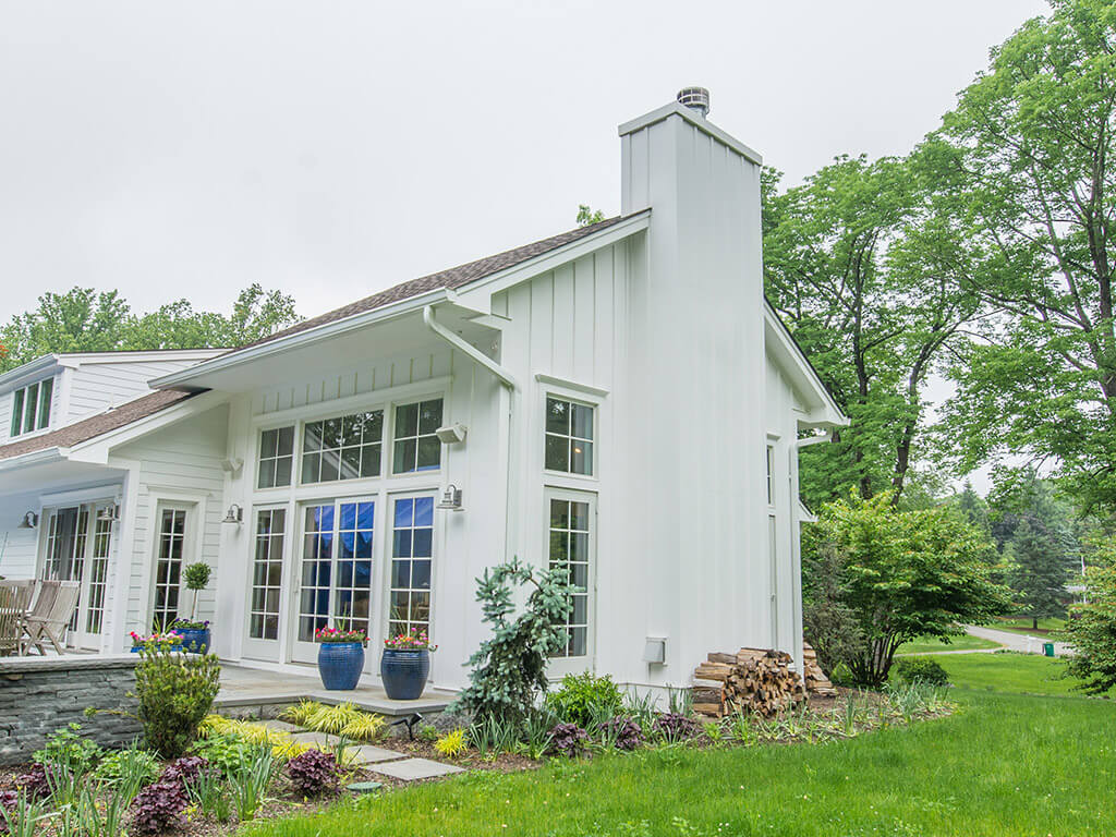 Exterior view of rustic Family room remodel board and batten siding  with deep overhang, zero clearance fire place and window wall with Andersen windows in Boonton, NJ renovated by JMC Home Improvement Specialists