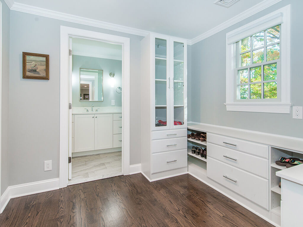 White master bedroom closet with custom shelving and drawers, hardwood floor and entrance to master bathroom In Springfield, New Jersey renovated by JMC Home Improvement Specialists