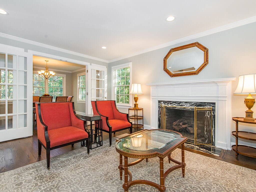 Family room with custom wood paneled fireplace, hardwood floor throughout and french door entrance to dining room in Springfield, New Jersey renovated by JMC Home Improvement Specialists