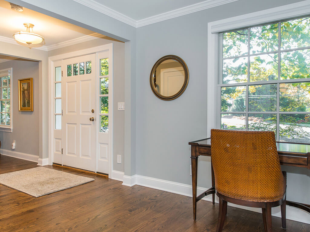 Front door entrance with side transoms, hardwood floor with white trim and grey interior walls in Springfield, NJ renovated by JMC Home Improvement Specialists