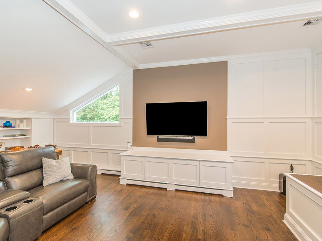 Custom white entertainment area with vaulted ceiling and custom heat covers and hardwood floor in family room In Randolph, New Jersey renovated by JMC Home Improvement Specialists