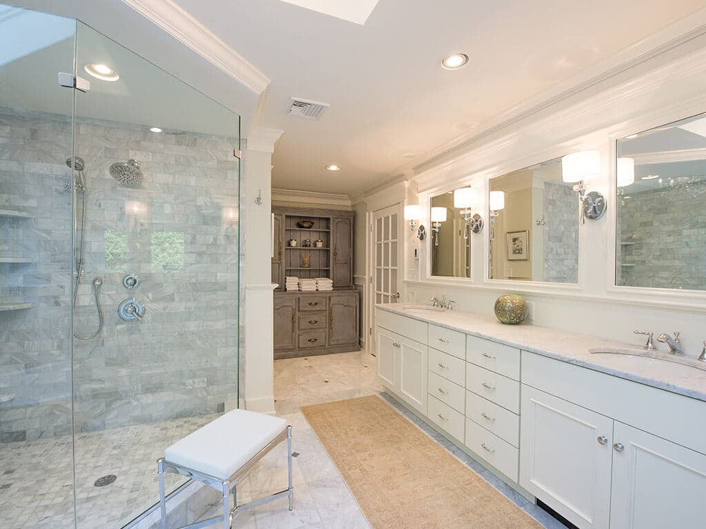 Custom gray cabinets in white master bath with frameless glass walk-in shower with Carrera marble and dual vanity with triple mirror and sconces with chrome fixtures in Sparta, NJ Renovated by JMC Home Improvement Specialists