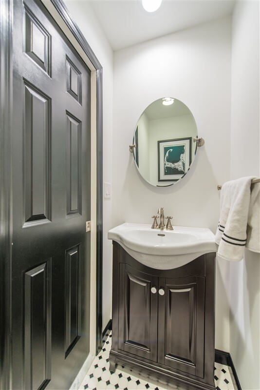 Black and white powder room with oval mirror in Bernardsville, NJ renovated by JMC Home Improvement Specialists