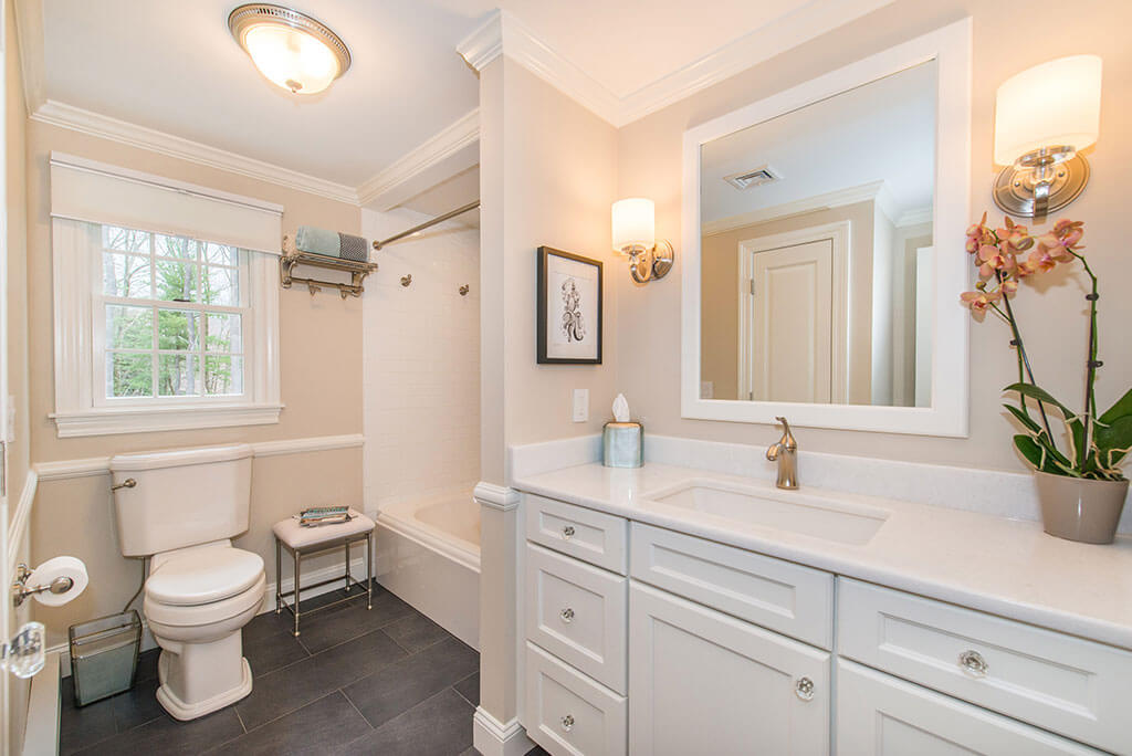 Hall bathroom remodel with white framed mirror and white vanity, shower and tub, with crown molding in Boonton, NJ renovated by JMC Home Improvement Specialists