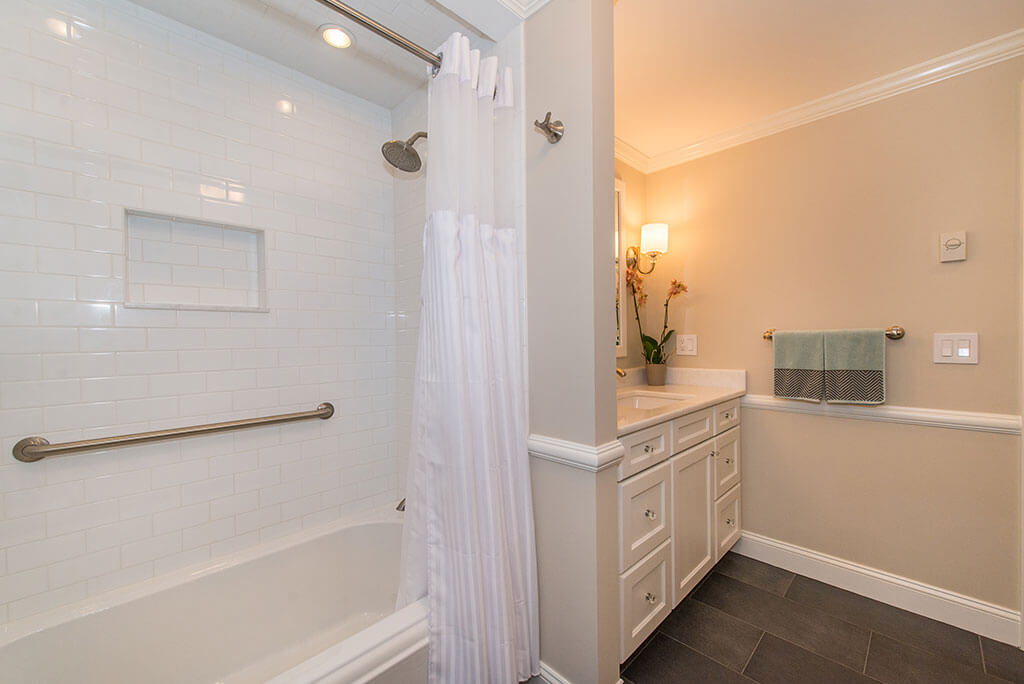 Hall bathroom remodel with white vanity, shower with subway tile, grab bar, niche, shower curtain and tub, with crown molding in Boonton, NJ renovated by JMC Home Improvement Specialists