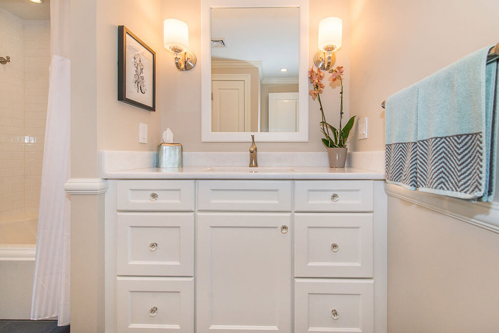 Hall bathroom remodel white vanity with quartz top and white framed mirror frame with sconces in Boonton, NJ renovated by JMC Home Improvement Specialists