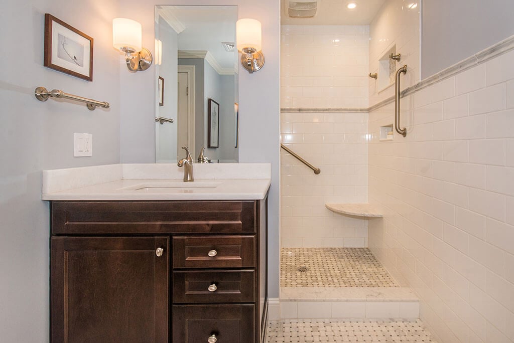 Boonton, NJ Master bathroom remodel espresso vanity with Carrera marble top, corner seat in shower with subway tile and grab bars, and basketweave floor renovated by JMC Home Improvement Specialists