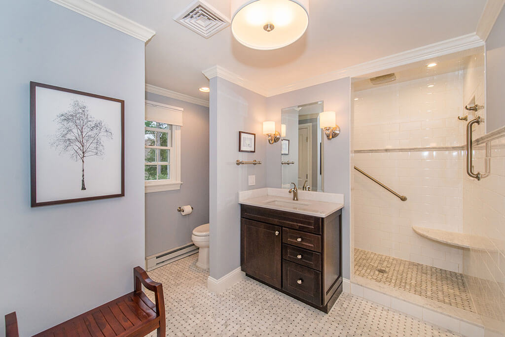 Boonton, NJ Large Master bathroom remodel corner espresso vanity with Carrera marble top, corner seat in shower with subway tile and grab bars, and basketweave floor renovated by JMC Home Improvement Specialists