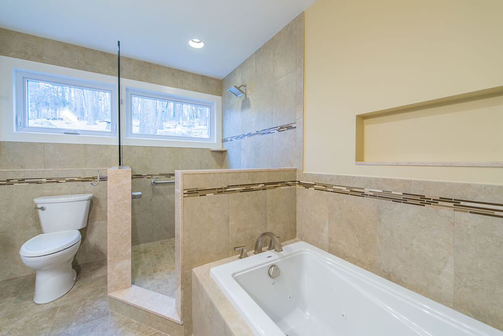 Boonton, NJ Master bathroom remodel with open shower and glass panel with window and separate tub with niche and mosaic wall tile with glass stripe renovated by JMC Home Improvement Specialists