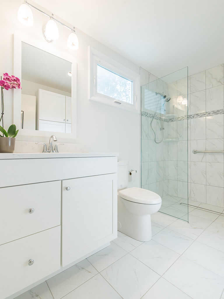 White handicap bathroom remodel with mosaic tile with accent stripe in roll-in shower with linear shower drain and glass panel with white vanity and quartz countertop in Mount Tabor, NJ renovated by JMC Home Improvement Specialists