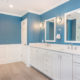 Master bathroom remodel with white wall paneling, blue painted, wood like tile floor, white shaker his and hers vanity with quartz counters and white framed mirrors with sconces in Chester, NJ renovated by JMC Home Improvement Specialists