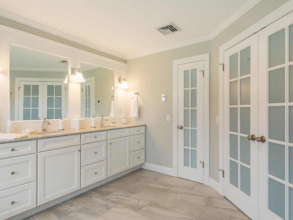 Master bathroom remodel with white shaker vanity with quartz countertop, custom wood trim mirrors with sconces, and linen storage closet, and French doors in Morris County, NJ renovated by JMC Home Improvement Specialists 