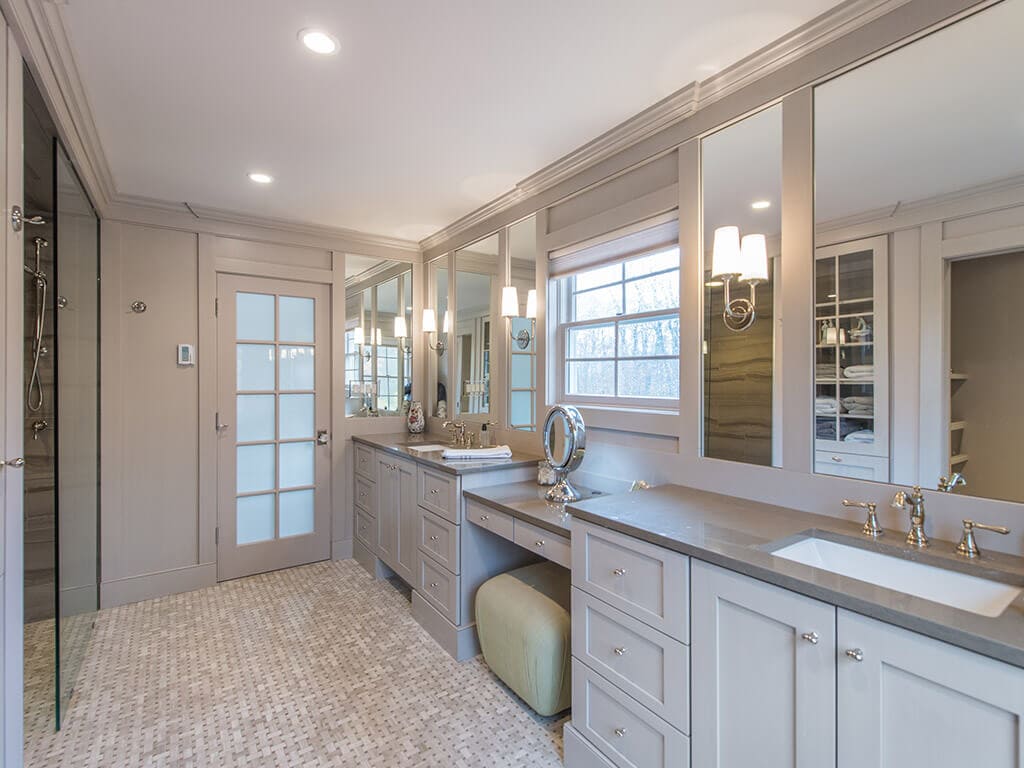 Award winning master bathroom remodel with monochromatic taupe, basket weave tile, frosted French door, make-up table, separate his and her shaker cabinet vanities, custom wood framed mirrors with sconces in Boonton, NJ renovated by JMC Home Improvement Specialists