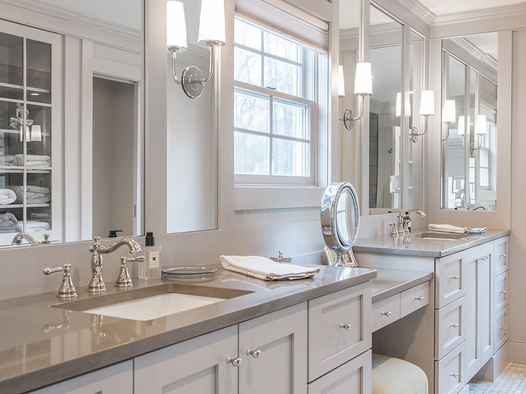 Elegant award-winning master bathroom remodel with separate vanities, rectangular undermount sinks, quartz counters, heated basketweave floor, custom wood framed mirrors, sconces in monochromatic taupe in Boonton, NJ renovated by JMC Home Improvement Specialists