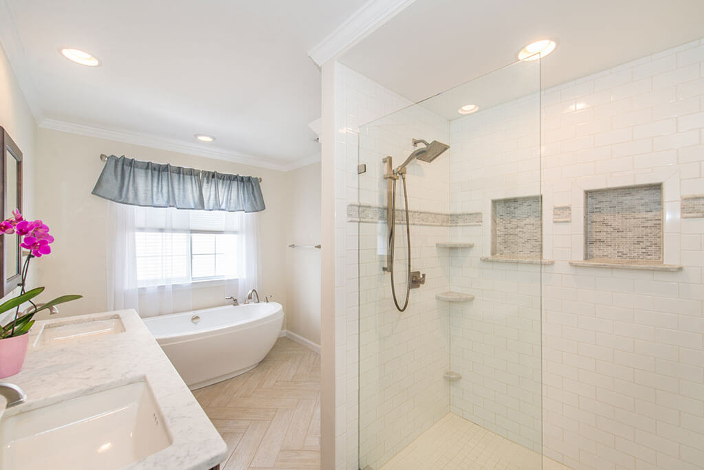 Master bathroom remodel with his and hers vanity, rectangular undermount sinks with granite counters, white shower with grey niches, clear glass shower door panel and soaking tub in Lake Hopatcong, NJ renovated by JMC Home Improvement Specialists