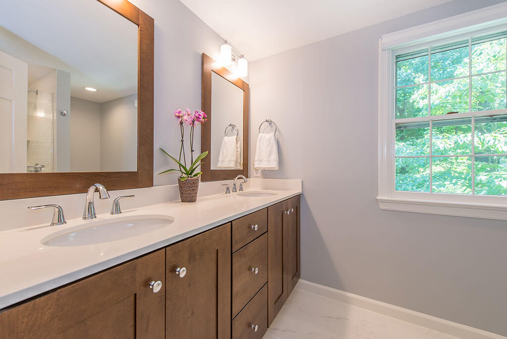 Master bathroom remodel with his and hers wood vanity, quartz counters, wood framed mirrors and chrome finishes in Mendham, NJ renovated by JMC Home Improvement Specialists