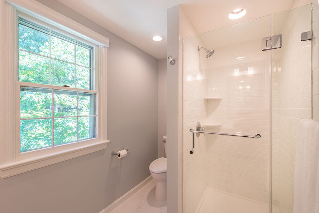 Master bathroom remodel with clear glass shower door, white subway tile and corner shelves in shower and grey painted walls in Mendham, NJ renovated by JMC Home Improvement Specialists