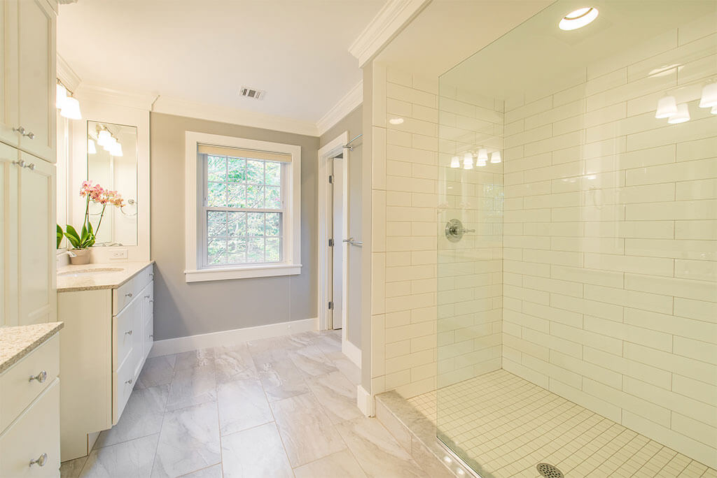 Master bathroom remodel in Morristown, NJ with white subway tile in shower with clear glass panel, quartz counters and grey painted walls with white crown molding renovated by JMC Home Improvement Specialists