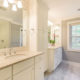 Master bathroom remodel with his and hers separate white vanities, quartz counters, linen cabinet and grey painted walls with white crown molding in Morristown, NJ renovated by JMC Home Improvement Specialists