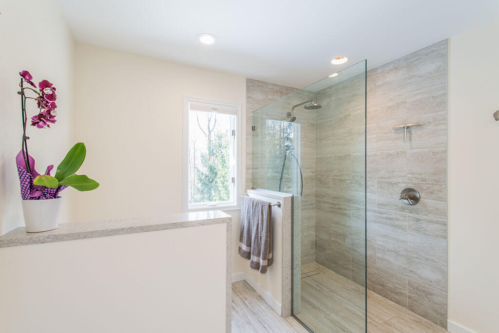 Master bathroom remodel with curbless, roll-in shower with frameless glass panel, Kohler hydro rail and  half wall by toilet in Chester, NJ renovated by JMC Home Improvement Specialists