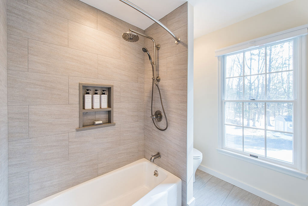 Hall bathroom remodel with tub and curved shower curtain, built in niche and grey tile in Chester, NJ renovated by JMC Home Improvement Specialists