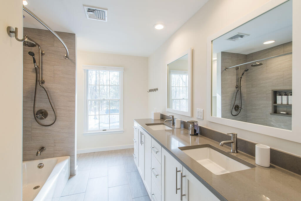 Hall bathroom remodel with tub and curved shower curtain, white shaker dual vanity with quartz counters and grey tile in Chester, NJ renovated by JMC Home Improvement Specialists