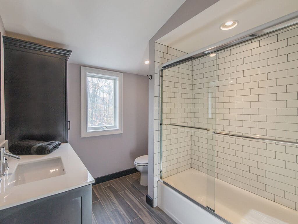 Bathroom remodel with wood like tile floor, black cabinets, subway tile with grey grout in shower in Boonton, NJ renovated by JMC Home Improvement Specialists