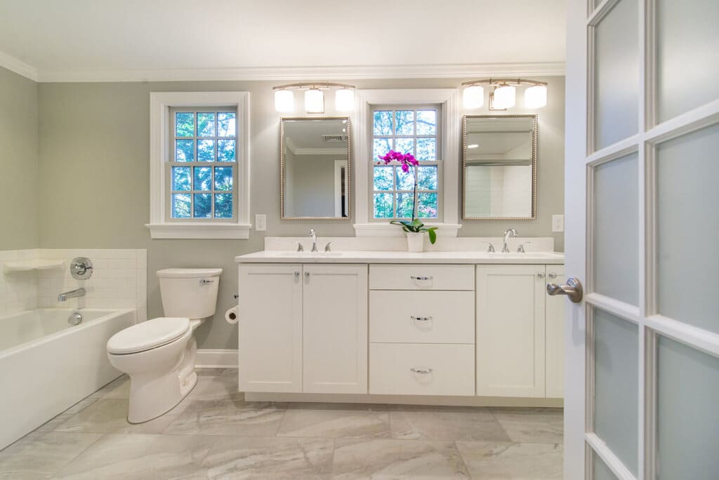 White bathroom remodel with French door, dual vanity, tub, chrome finishes and grey walls in Springfield, NJ renovated by JMC Home Improvement Specialists