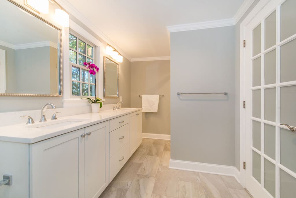 White bathroom remodel with frosted glass french door, chrome finishes and grey walls, dual white vanity, quartz counter, undermount sinks, decorative mirrors in Springfield, NJ renovated by JMC Home Improvement Specialists