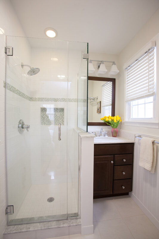 Small bright white traditional bathroom remodel with espresso vanity, black and white tile, wainscoting, niche in shower in Chatham, NJ renovated by JMC Home Improvement Specialists 