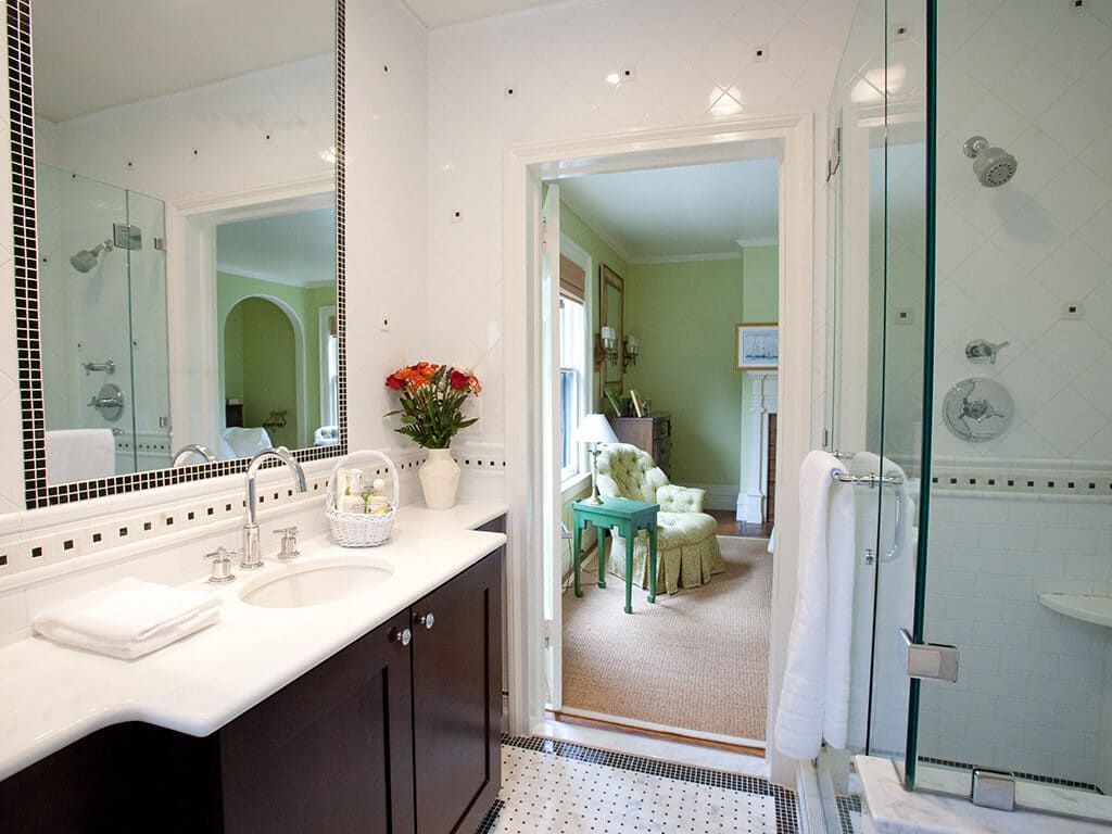 Black and white master bathroom remodel with espresso and marble vanity, tile around mirror, basketweave floor, Carrera tiles and clear glass panel shower door in Morristown, NJ renovated by JMC Home Improvement Specialists