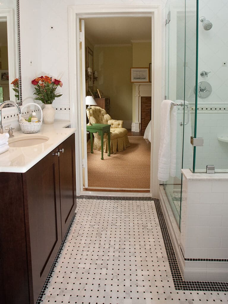 Master bathroom remodel with espresso and marble vanity, undermount sink, chrome finishes, tile around mirror, basketweave floor and black and white Carrera tiles in Morristown, NJ renovated by JMC Home Improvement Specialists