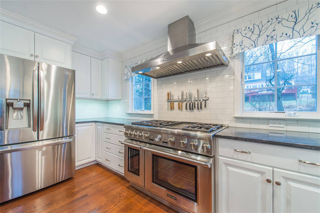 Kitchen remodel with hardwood flooring, white shaker cabinets, crown molding, industrial range, subway tile backsplash, freestanding hood in Bernardsville, NJ renovated by JMC Home Improvement Specialists