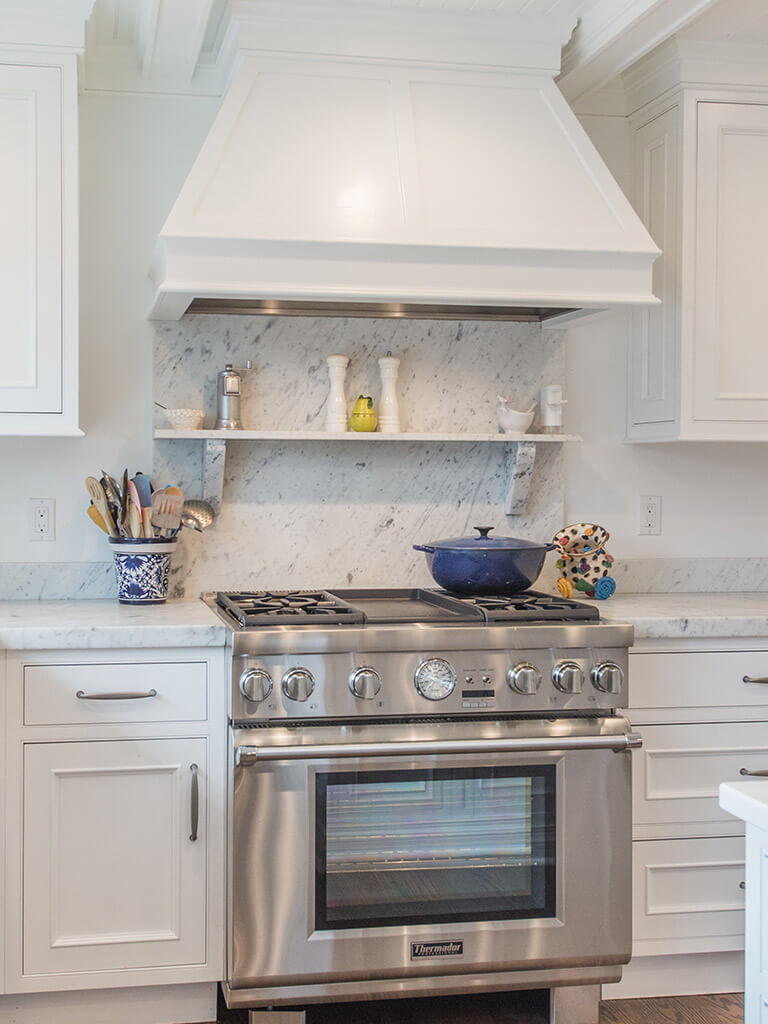 Custom white wood hood over 36” range with marble backsplash and shelf in Boonton, NJ renovated by JMC Home Improvement Specialists