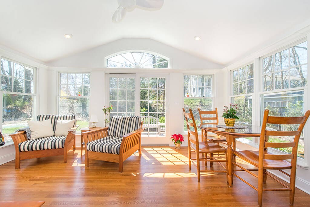 Sunroom with vaulted ceilings, ceiling fan, highhats, hardwood flooring and transom window over French doors in Chatham, NJ renovated by JMC Home Improvement Specialists