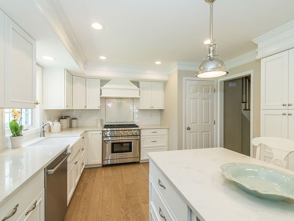  White kitchen remodel with shaker cabinets, quartz countertops, subway tile backsplash, custom wood hood, crown molding and hardwood flooring in Morris County, NJ renovated by JMC Home Improvement Specialists