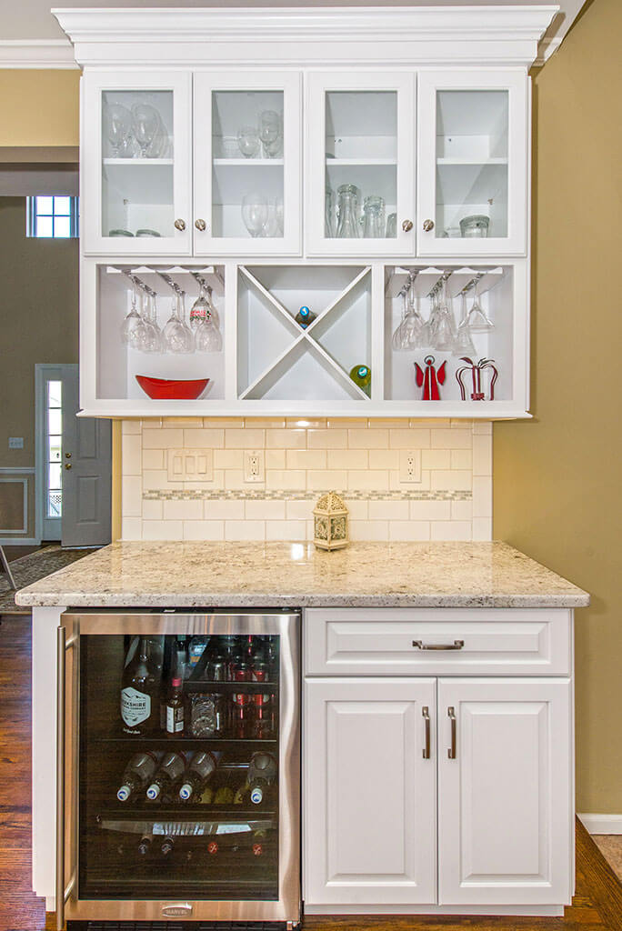 Custom bar in kitchen remodel with white cabinetry, granite counter, subway tile backsplash with mosaic strip, stainless wine fridge and hardwood floor throughout in Morris County, NJ renovated by JMC Home Improvement Specialists