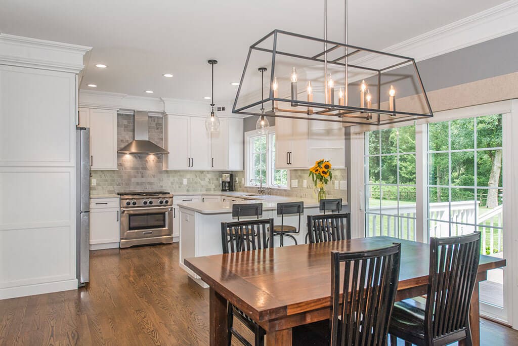 White open concept kitchen remodel with shaker cabinets, quartz counters, peninsula, freestanding metal hood and marble backsplash in Florham Park, NJ renovated by JMC Home Improvement Specialists