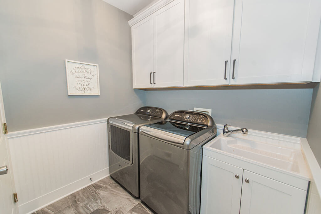 White and grey laundry room remodel with shaker cabinets with crown molding with slop sink in Florham Park, NJ renovated by JMC Home Improvement Specialists