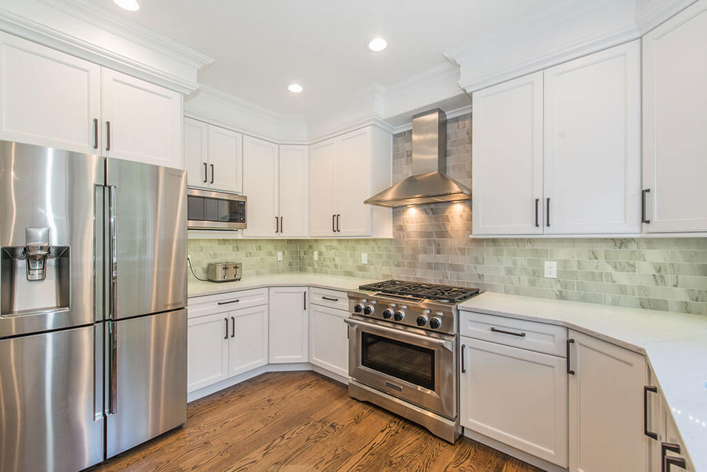 White kitchen remodel with shaker cabinets with crown molding, quartz counters marble subway tile backsplash, undercabinet lighting, freestanding stainless hood, stainless appliances in Florham Park, NJ renovated by JMC Home Improvement Specialists