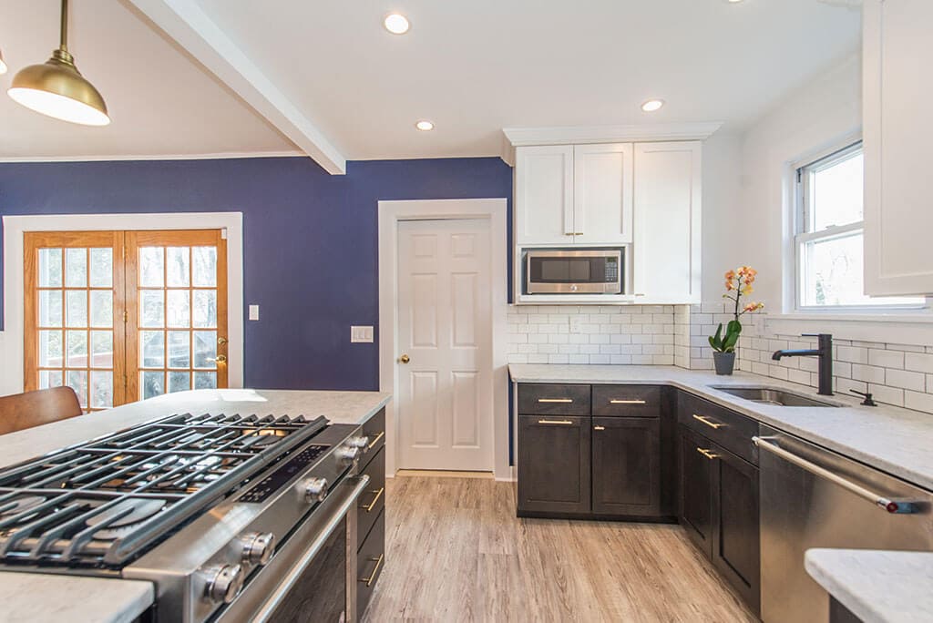 Black and white kitchen remodel with white upper cabinets, black lower cabinets, white subway tile, wall removed with exposed beam in Montclair, NJ renovated by JMC Home Improvement Specialists