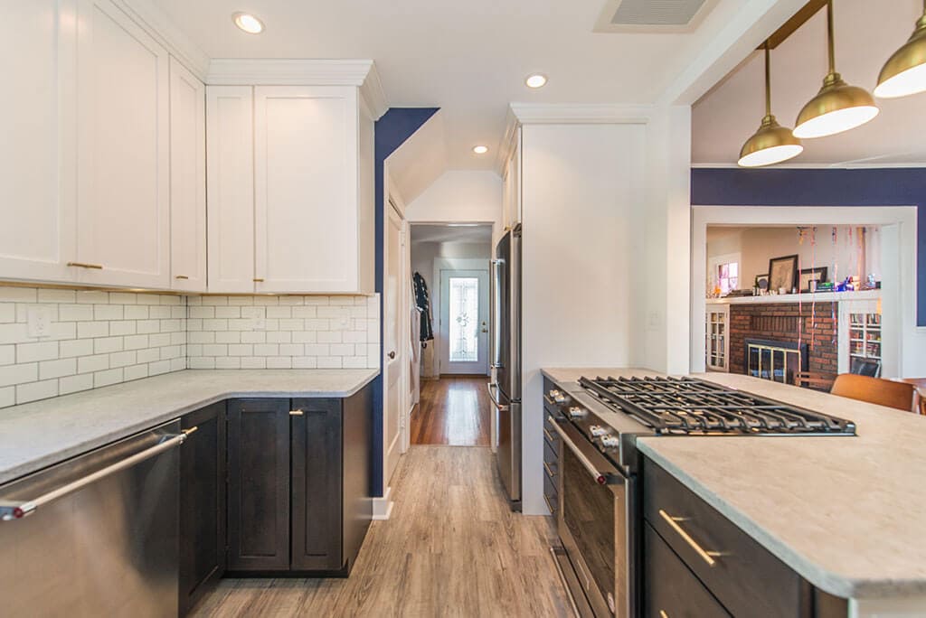 Black and white kitchen remodel with white upper cabinets, black lower cabinets, white subway tile backsplash, peninsula with quartz counters, wall removed with exposed beam in Montclair, NJ renovated by JMC Home Improvement Specialists