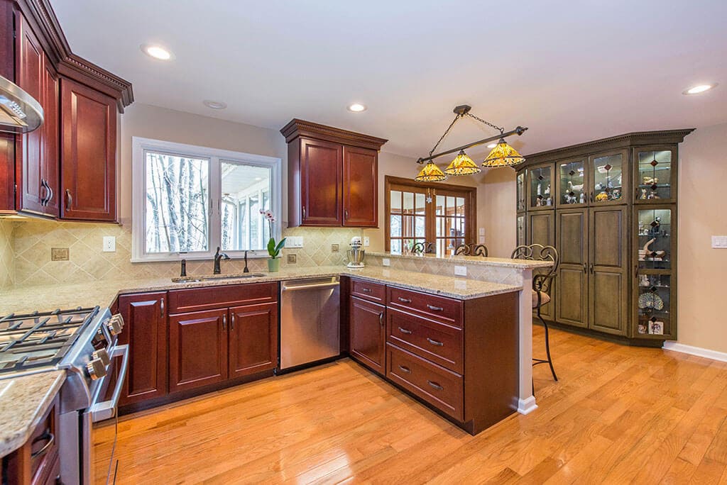Cherry kitchen cabinets with green accent, mosaic backsplash and granite counters in Morris Plains, NJ renovated by JMC Home Improvement Specialists