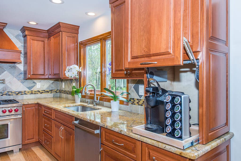 Wood cabinetry in kitchen remodel with hidden coffee station, granite counters, mosaic tile backsplash in Morristown, NJ renovated by JMC Home Improvement Specialists