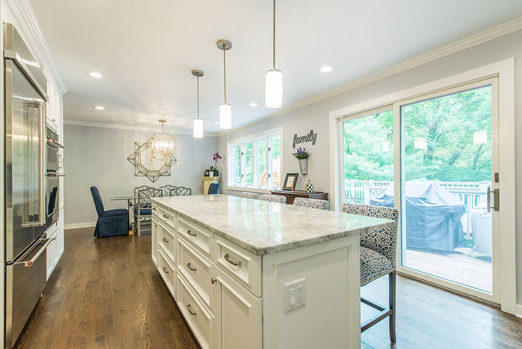 Open concept white kitchen remodel extended kitchen island for seating, granite counters, pendant lights above island and LED highhats, hardwood flooring in Morristown, NJ renovated by JMC Home Improvement Specialists