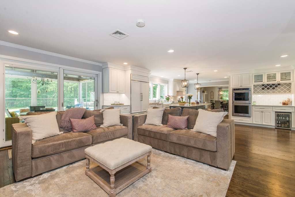 Open concept white kitchen remodel with white panel fridge, double oven, bar fridge, wine rack and hardwood floor throughout in Denville, NJ remodeled by JMC Home Improvement Specialists